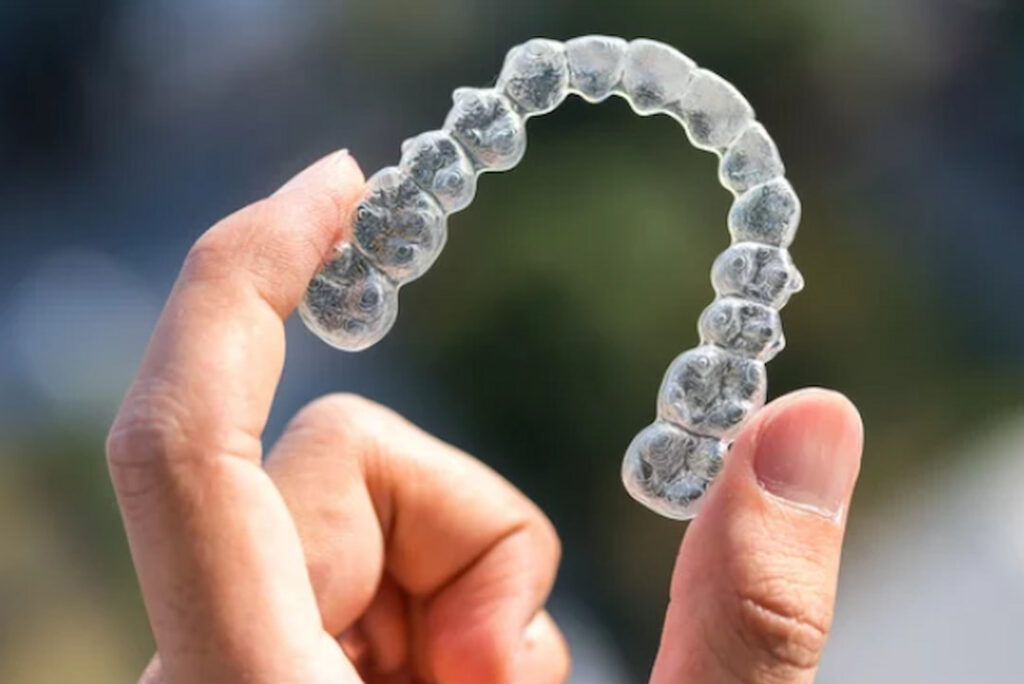 a person holding aligners in hand