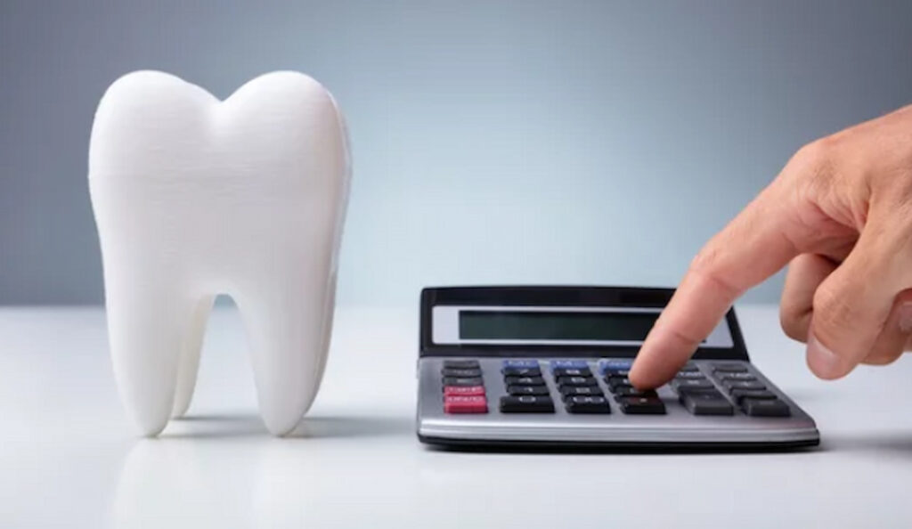 a person's finger on a calculator and a tooth model