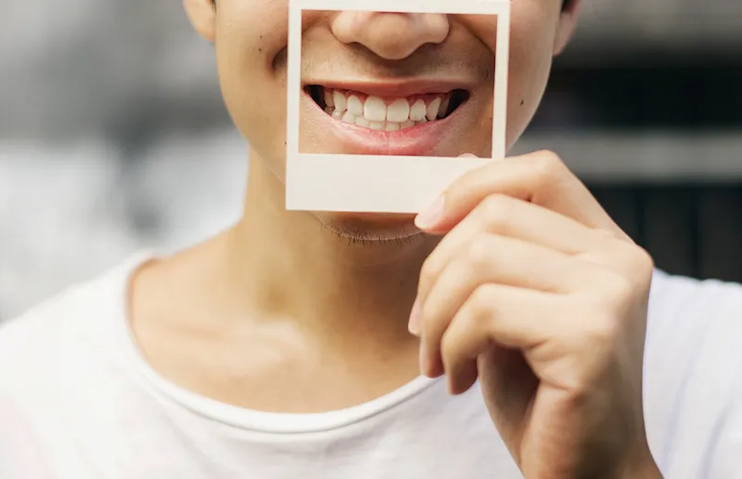 a person holding a paper frame over his smile