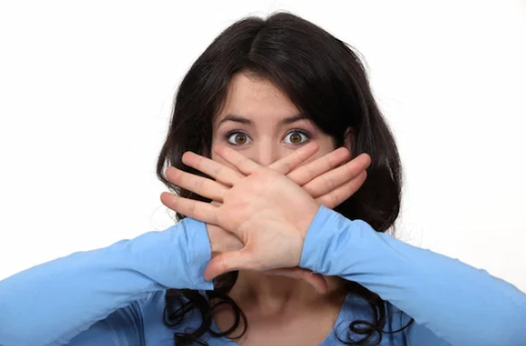 a woman with crossed hands over her mouth
