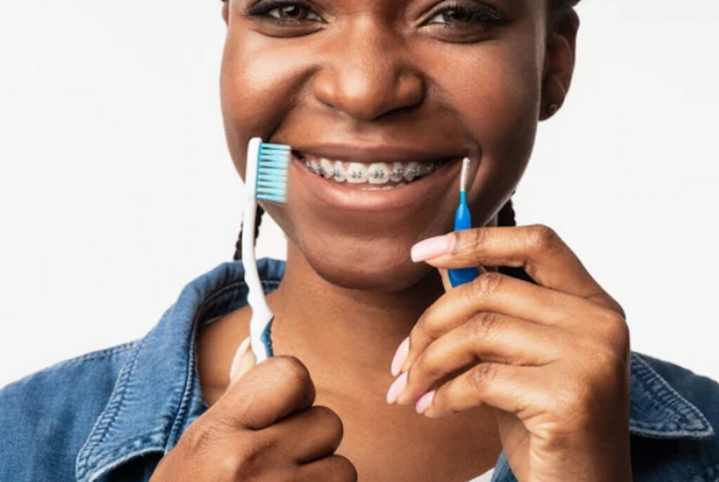 a smiling woman holding two brushes for braces in her hands