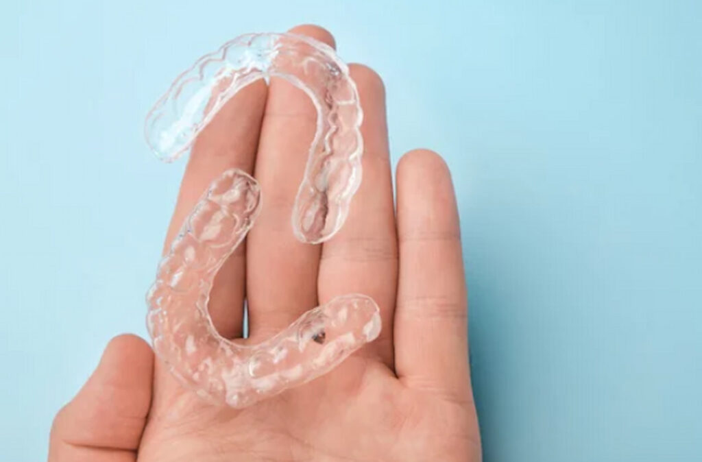 a person holding aligners in their hand