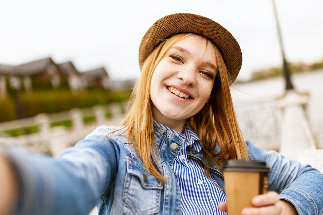 a girl with hat holding coffee outdoors