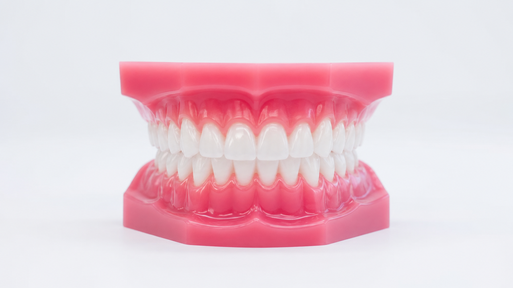 A pair of clear removable aligner trays held in open hands