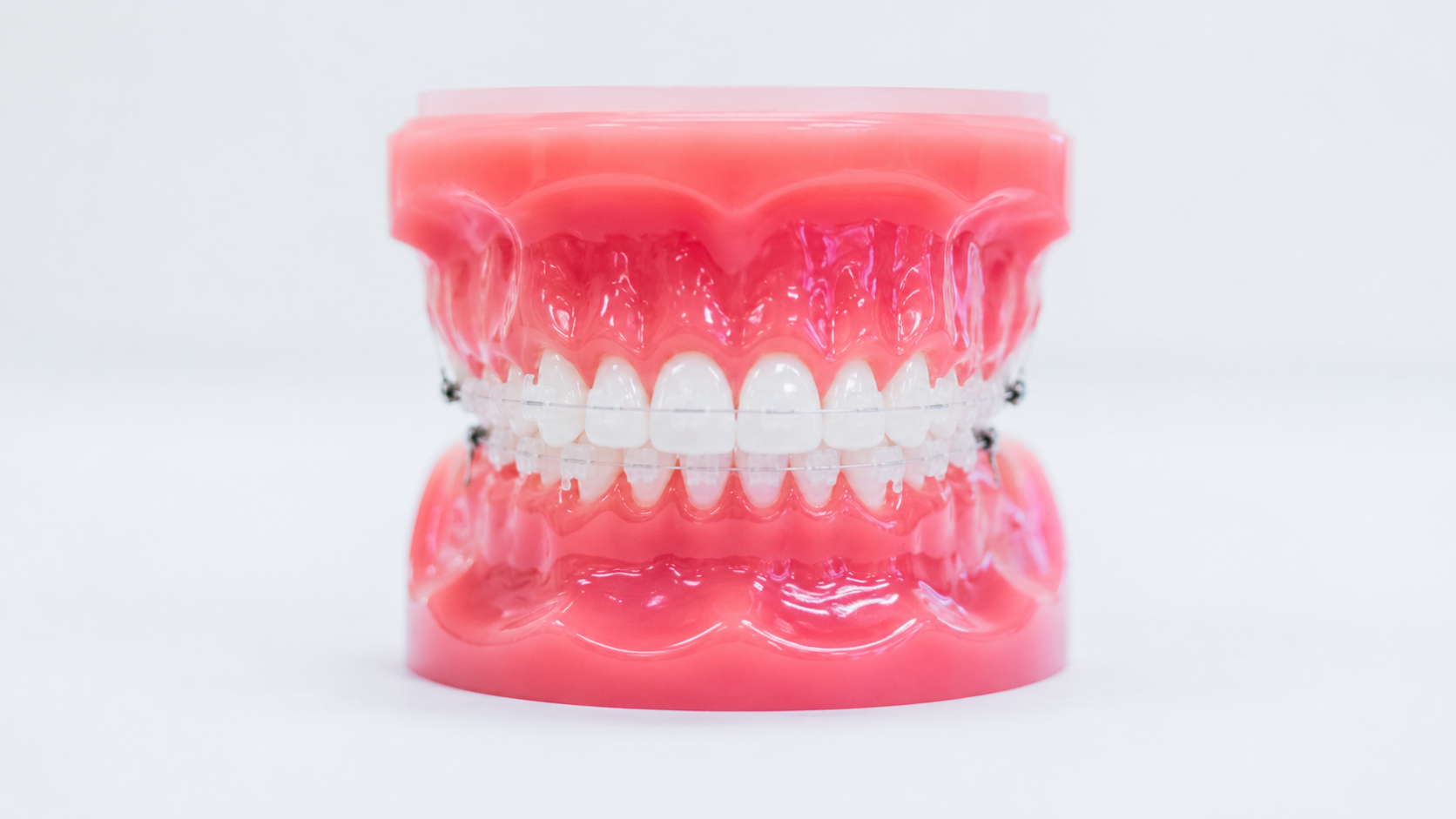 A smiling patient holding a clear Invisalign aligner and its case